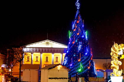 Oświetlona choinka na tle architektury Kowna zimą.