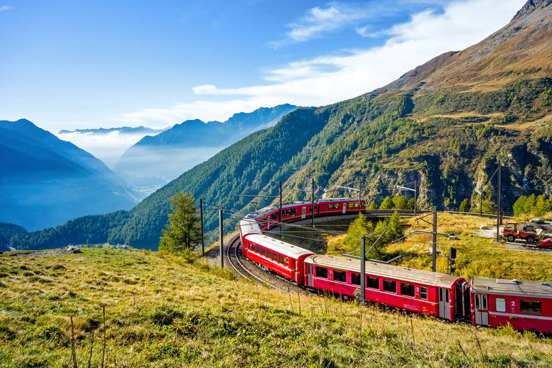 Czerwony pociąg Bernina Express jedzie po krętym torze przez góry w Alpach Szwajcarskich.