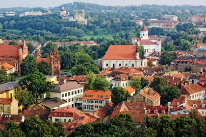 Panorama Wilna z czerwonymi dachami i zielenią drzew.