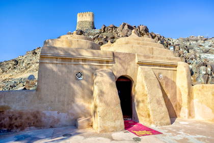 Fort Al Badiyah, beżowy budynek z kopułami na wzgórzu w Zjednoczonych Emiratach Arabskich.