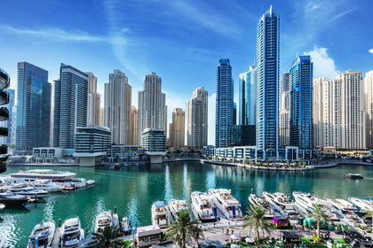 Panorama Dubaju: wieżowce i jachty na morzu.