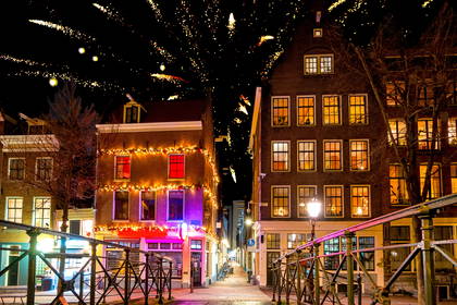 Nocny widok na kanał w Amsterdamie. W tle budynki i sztuczne ognie.