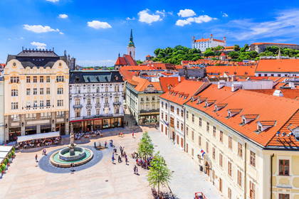 Panorama Bratysławy z rynkiem, fontanną i zamkiem na wzgórzu.