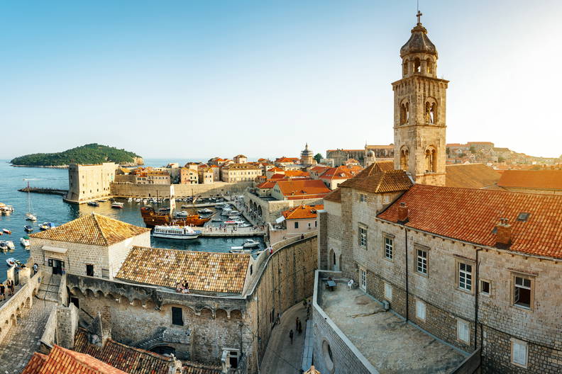 Panorama Dubrownika z charakterystycznymi czerwonymi dachami i wieżą kościoła.