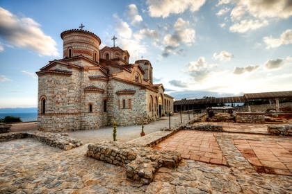 Cerkiew św. Jana Teologa w Kaneo, Macedonia. Kamienny budynek z kopułami zwieńczonymi krzyżami.