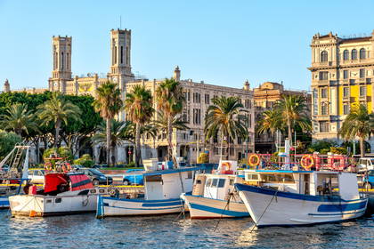 Port w Cagliari z łodziami i budynkami w tle.