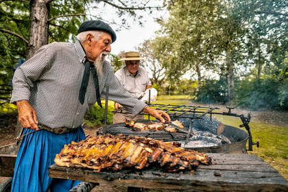 Dwóch mężczyzn przygotowuje argentyńskie asado na zewnątrz.