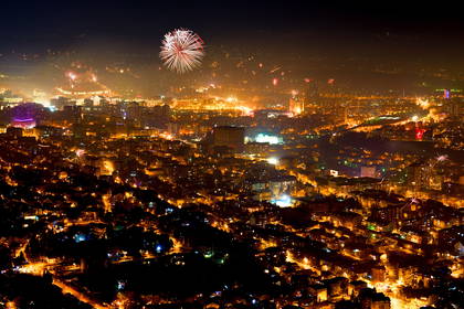 Nocna panorama Skopje rozświetlona miejskimi światłami i fajerwerkami.
