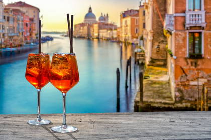 Dwa drinki Aperol Spritz z widokiem na wenecki kanał.