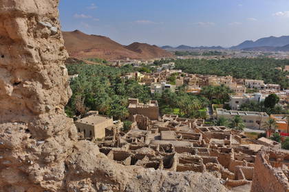 Panorama miasta Nizwa w Omanie. Widok na starą architekturę, palmy i góry w tle.