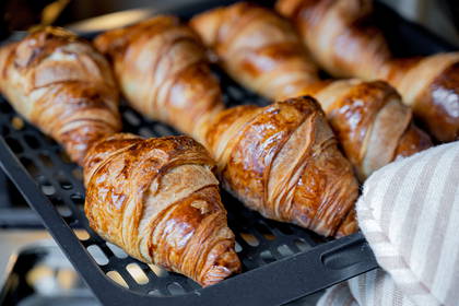 Rumiane croissanty na czarnej blasze.