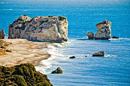 Krajobraz Pafos na Cyprze: formacje skalne w morzu i piaszczysta plaża.