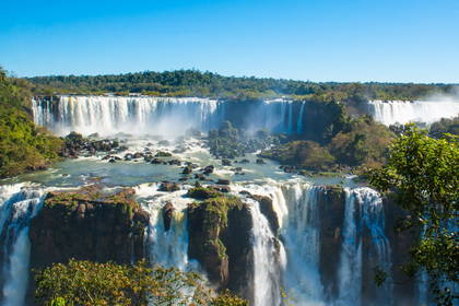 Wodospady Iguazu otoczone zielenią, uchwycone z szerokiej perspektywy.