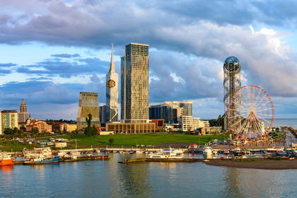 Panorama Batumi z portem, wieżami i diabelskim młynem w tle.