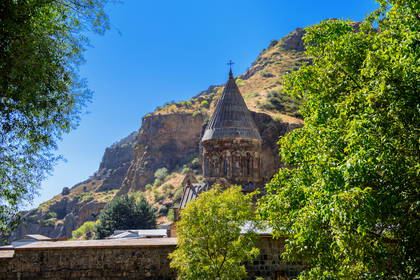 Klasztor Geghard z wysoką wieżą na tle skalnego klifu, Armenia.