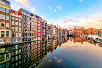 Kolorowe kamienice w Amsterdamie odbijają się w wodach kanału.