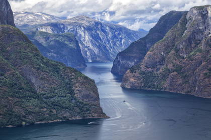 Fiord z łodziami płynącymi między stromymi zboczami gór.
