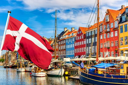 Nyhavn w Kopenhadze: kolorowe kamienice i zacumowane łodzie pod duńską flagą.