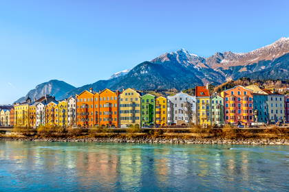 Kolorowe budynki w Innsbrucku nad rzeką Inn z widokiem na góry.