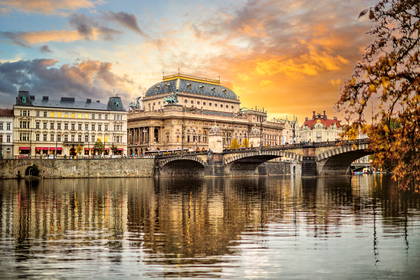 Panorama Pragi o zachodzie słońca: Teatr Narodowy i most na Wełtawie.