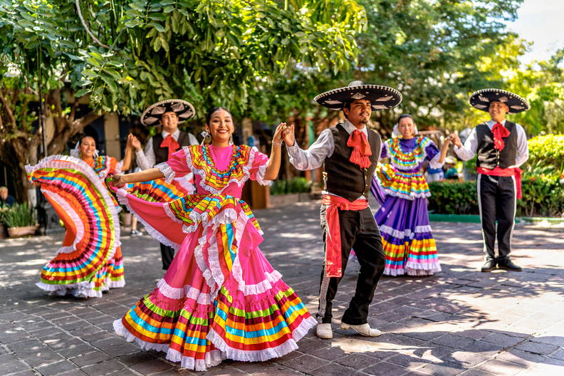 Zespół tancerzy w barwnych strojach ludowych i sombrerach.