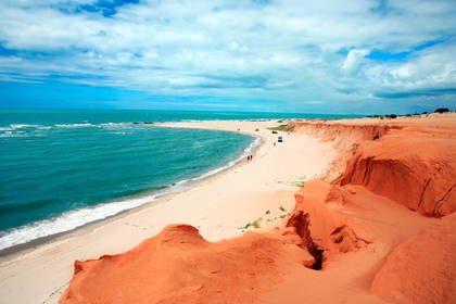 Plaża z turkusowym oceanem i pomarańczowymi klifami.