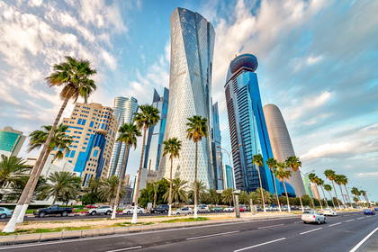 Drapacze chmur w Doha, Katar, widoczne z drogi obsadzonej palmami.