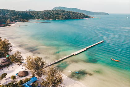 Widok z lotu ptaka na plażę, pomost i łodzie.
