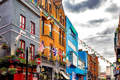 Ulica w Dublinie z kolorowymi budynkami ozdobiona flagami.