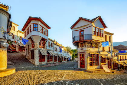 Zabytkowe, kamienne domy przy brukowanej uliczce Starego Bazaru w Gjirokastrze, w Albanii.