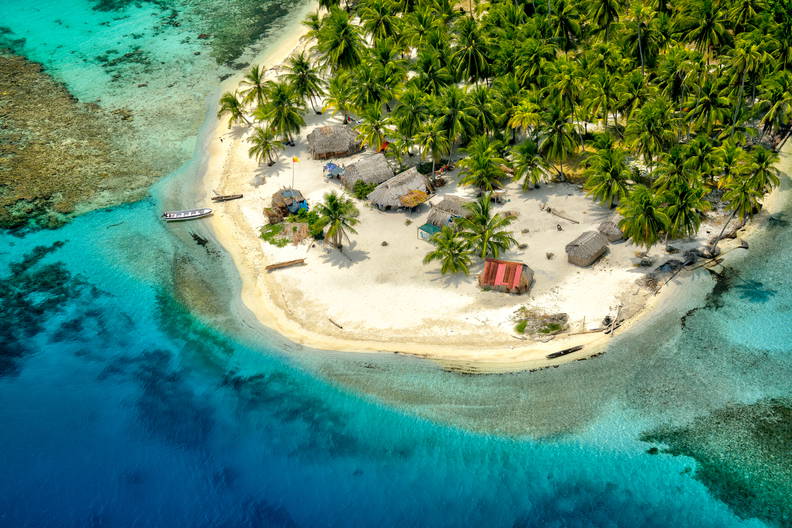 Tropikalna wyspa z palmami i chatami, widok z lotu ptaka.
