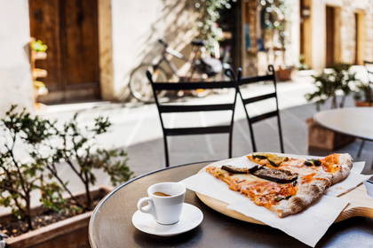 Pizza i espresso na stoliku w restauracji na świeżym powietrzu.