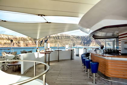 Bar na statku z widokiem na morze i góry Santorini w Grecji.