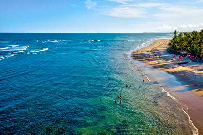 Plaża z lotu ptaka: spokojny ocean i wypoczywający ludzie.