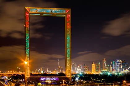 Dubajska Rama na tle nocnej panoramy miasta.