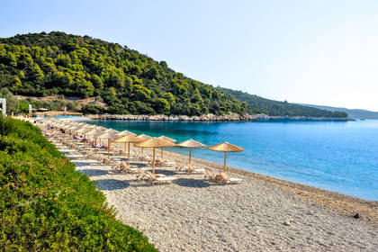 Plaża z parasolami i leżakami nad turkusowym morzem.