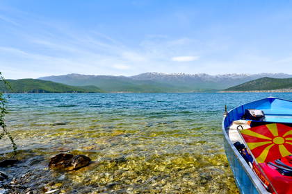 Jezioro Prespa z łodzią i flagą Macedonii Północnej na maszcie.