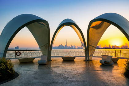 Panorama Dubaju o zachodzie słońca, widoczna zza rzeźbionej ramy.