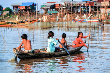 Czworo dzieci płynie łodzią po jeziorze Tonle Sap w Kambodży.