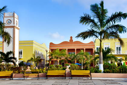 Plac w San Miguel de Cozumel z kolorowymi budynkami i palmami.