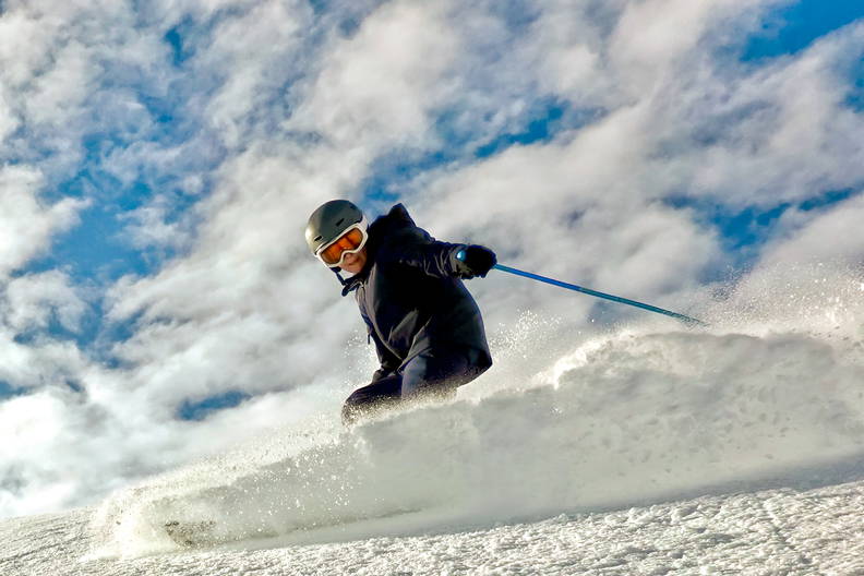 Narciarz zjeżdża po ośnieżonym stoku.