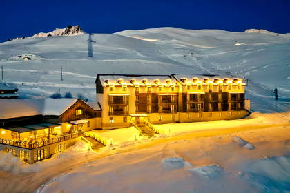 Oświetlony hotel nocą na tle ośnieżonych stoków w Gudauri.