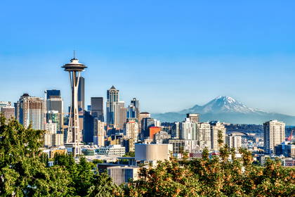Słoneczna panorama Seattle z wieżą Space Needle i ośnieżonym szczytem Mount Rainier w tle.