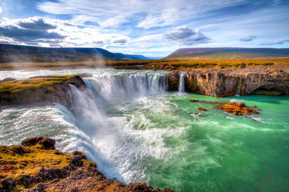 Szeroki, kaskadowy wodospad Godafoss na Islandii. Turkusowa woda wpada do skalistego kanionu.