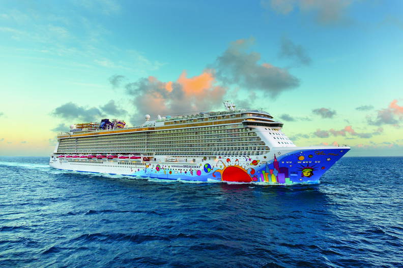 O zachodzie słońca po oceanie płynie statek wycieczkowy Norwegian Breakaway z kolorową grafiką na kadłubie.
