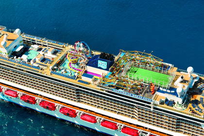 Widok z lotu ptaka na statek Norwegian Breakaway z aquaparkiem, basenami i boiskiem sportowym na górnym pokładzie.