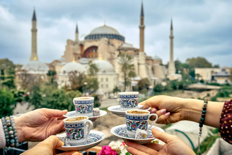 Cztery filiżanki z kawą po turecku w dłoniach na tle Hagia Sophia.