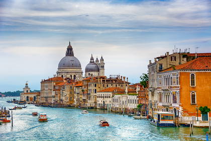 Widok na Canal Grande w Wenecji. Na wodzie płyną łodzie, a w oddali widać Bazylikę Santa Maria della Salute.