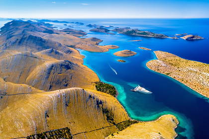 Park Narodowy Kornati w Chorwacji z lotu ptaka: skaliste wyspy, lazurowe morze i biały jacht w zatoce.