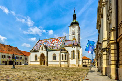 Kościół św. Marka w Zagrzebiu na brukowanym placu. Dach zdobią kolorowe płytki ułożone we wzory herbów.